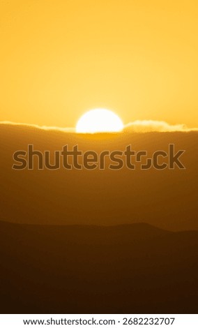 A sun is setting in the sky, casting a warm glow over the mounta