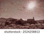 The sun shines brightly over the ghost town of Bodie, California, casting light on the abandoned wooden buildings of this 19th-century mining town preserved at Bodie State Historic Park.