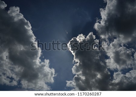 The sun shines on a white cloud in the blue sky 