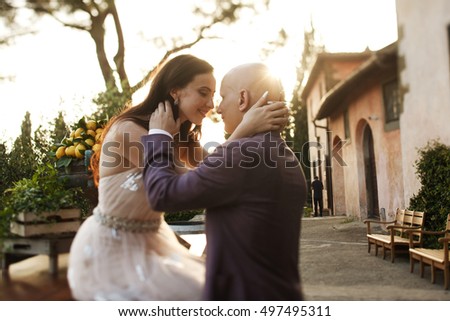 Sun shines over man holding woman's head while she sits on the table with lemons