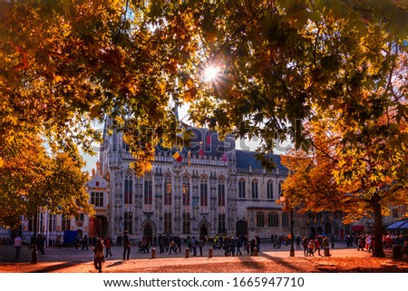 The sun shines through autumn leaves over the City Hall of Bruges in Belgium