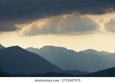 The sun shines through the clouds with outlined silhouettes of the Velebit mountains, Croatia