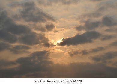The sun shining behind a gray cloud in the sky full of cloudy weather