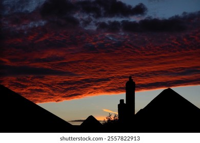 Sun shining onto evening cloud formations, setting on silhouetted suburb houses. Moody urban dusk silhouette. - Powered by Shutterstock