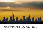 Sun shining through clouds above the silhouette of Warsaw city center.