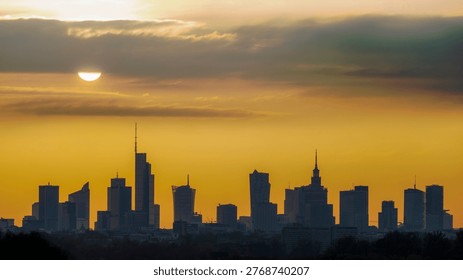 Sun shining through clouds above the silhouette of Warsaw city center.