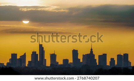Sun shining through clouds above the silhouette of Warsaw city center.