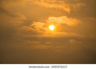 The sun is shining through the clouds, creating a warm and peaceful atmosphere. The sky is a mix of orange and gray, with the sun peeking through the clouds