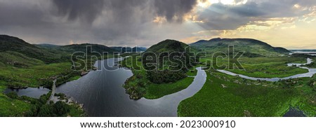 The sun shining through the clouds in the distance with Owengarriff River in the Killarney National Park in county Kerry Ireland in the foreground