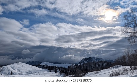Sun shining through clouds over snowy mountain landscape