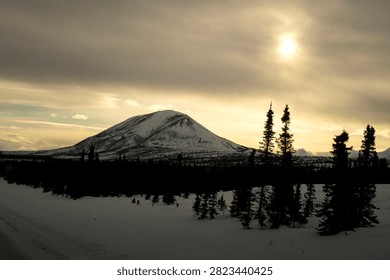 Sun shining through clouds over Donnelly Dome on a winter day in Alaska. 