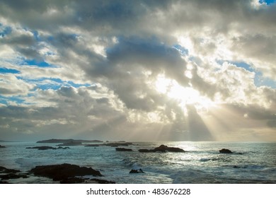 Sun shining through clouds over beach