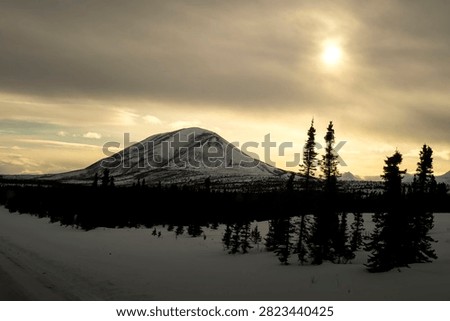 Sun shining through clouds over Donnelly Dome on a winter day in Alaska. 