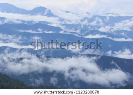 Sun shining through the clouds with silhouetted mountians