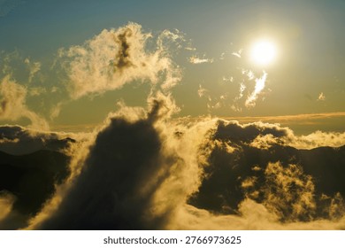 Sun Shining Through Dramatic Clouds Above Mountain at Sunset, above a dramatic sea of clouds filling the mountain valleys in Hokkaido
