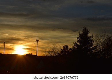 sun sinking between wind power plants