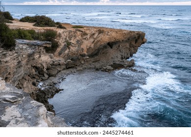 The sun slowly rises over jagged cliffs, which meet the rough turquoise waters of the Pacific Ocean along the Mahaulepu Heritage Trail in Koloa, Hawaii on the island of Kauai. - Powered by Shutterstock