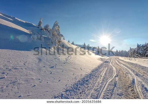 Sun, snow and car tracks\
on the road in the winter in the mountain. The concept of winter\
travel by car.
