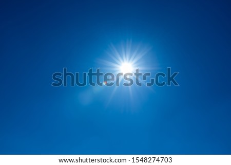 Sun, sunbeams against blue sky - cloudless sky. Photography with Lense flair effect