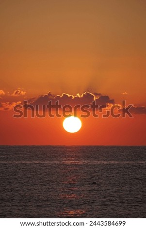 Sun at sunset between cloud and sea