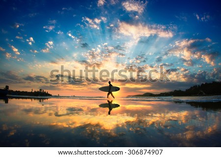 Sun surfer. A man is walking with a surf in his hands across the sea shore. 