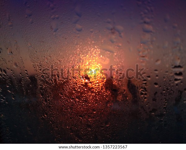 The sun through the car\
window with rain drops on sunrise. Blurred background with bokeh on\
sunset.