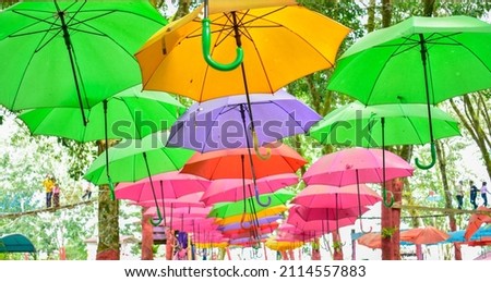 Sun umbrella against blue sky. A large number of colorful umbrellas hang on the background of the blue sky and in the trees or forest of tourist attractions