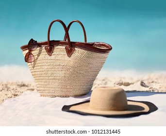 Sun vacation beach winter travel holiday background- Beach bag, fashion hat and sunglasses for Caribbean relaxation. . Copy space on blue ocean. Fashion stylish luxury accessories.