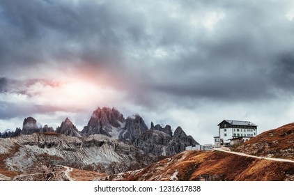 Sun which breaks through the clouds creates a colorful sight. Building standing high on the mountains near the bunch of cliffs with mist.