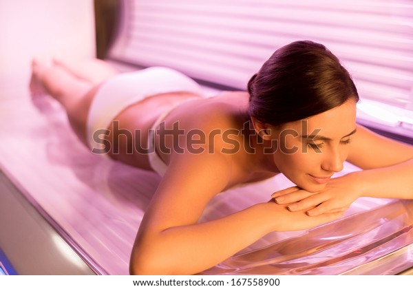 Sunbathing on tanning bed. Attractive young woman\
lying on tanning bed and\
smiling