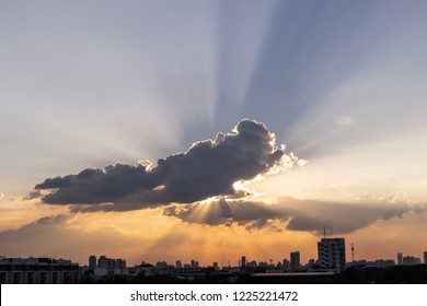 Sunbeam through the dramatic cloud during sunset time, with silhouette building below