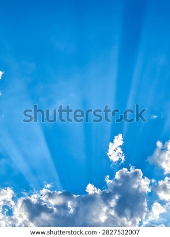 Sunbeams breaking through clouds into a clear blue sky, crepuscular rays