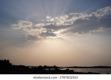 Sunbeams breaking through clouds over calm lake