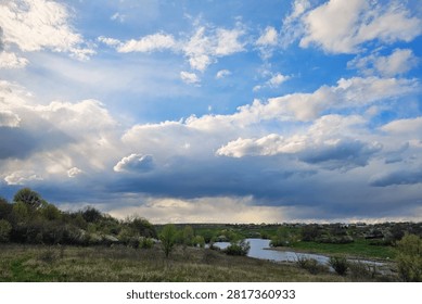 Sunbeams breaking through dramatic clouds over scenic spring river landscape