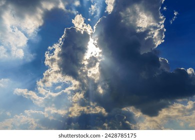 Sunbeams breaking through dramatic cumulus clouds. Weather change from stormy to sunny. Hope or religion concept.