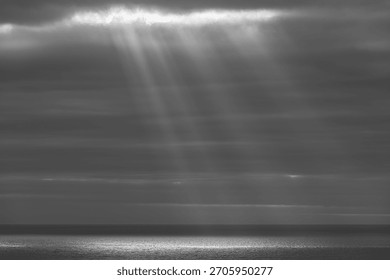 Sunbeams Breaking Through Heavy Clouds Over a Calm Ocean Surface at the Horizon
