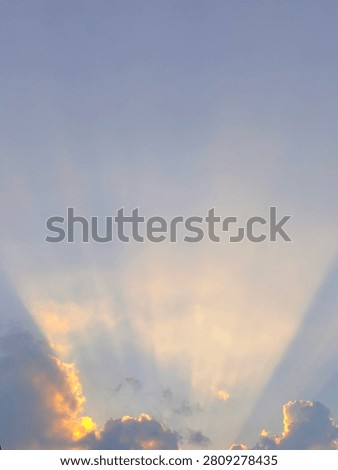 Sunbeams or crepuscular rays breaking through cumulus clouds during a golden sunset sky.