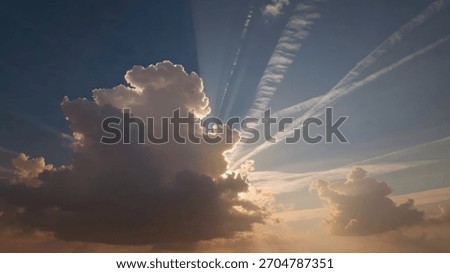 Sunbeams pierce through a dramatic sky, illuminating clouds and crisscrossing contrails, creating a sense of vastness and wonder.