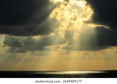 Sunbeams piercing through clouds over the endless sea