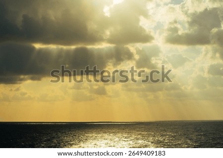 Sunbeams piercing through clouds over the endless sea