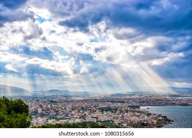 Sunbeams shining through the dramatic clouds over the city Chania. Toned
