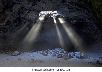 Sunbeams shooting down from a skylight inside lava tube cave
