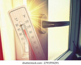 Sunbeams streaming through an open window and a thermometer during a heat wave	