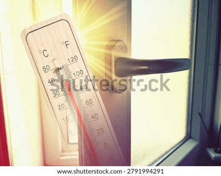 Sunbeams streaming through an open window and a thermometer during a heat wave	