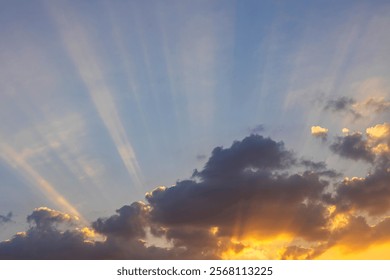 Sunbeams of sunlight breaking through the clouds in the evening with golden rays of sunshine.