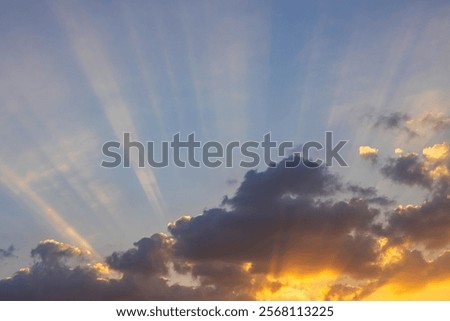 Sunbeams of sunlight breaking through the clouds in the evening with golden rays of sunshine.