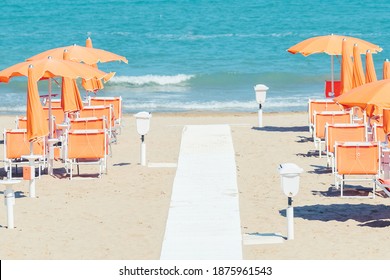 Sunbeds and parasols on the seashore. Beach, sea and umbrellas on summer day. Adriatic coast, Rimini, Italy, view from Gabicce Mare.
