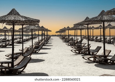 Sunbeds and umbrellas at Beach. Tropical beach, sunbeds and palm tree umbrellas. Beautiful white beach, umbrellas and sunbeds on beach on sunny day.