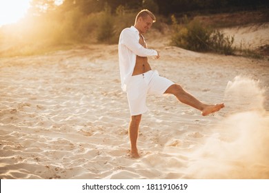 Sunburnt Man In White Clothes Running And Having Fun On The Beach At Sunset. Summer Vacation, Holyday, Wedding Near The Sea.