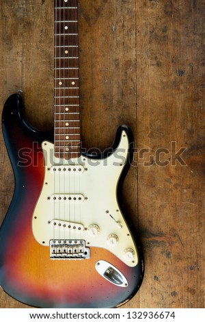 Sunburst color guitar with very old wood surface in background.